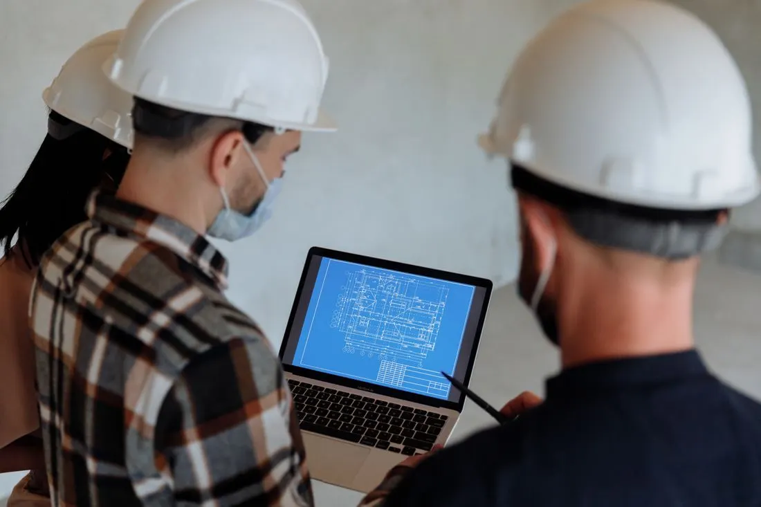Equipe de incorporadora revisando a planta de um empreendimento no laptop.